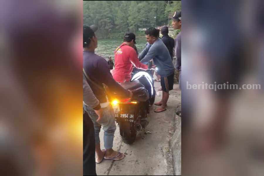 Warga di sekitar Telaga Sarangan dan petugas saat mengevakuasi motor PCX yang dikendarai dua pengunjung yang terperosok usai terhantam batu, Jumat (15/12/2023).