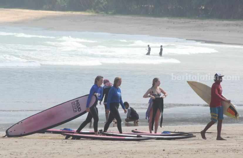 Wisatawan usai menikmati ombak dengan berselancar di pantai Pulau Merah yang menjadi salah satu destinasi wisata Banyuwangi yang menakjubkan. (rin/dok)