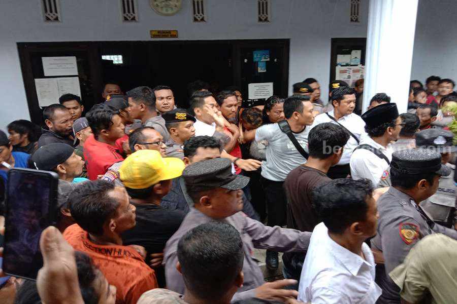 Sejumlah petugas kepolisian Polres Pasuruan saat mengevakuasi pelaku dari amukan warga.