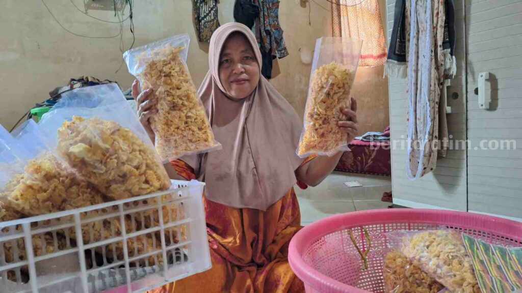 Jumani (47) menunjukkan emping jagung buatannya. [Foto : Misti/beritajatim.com]