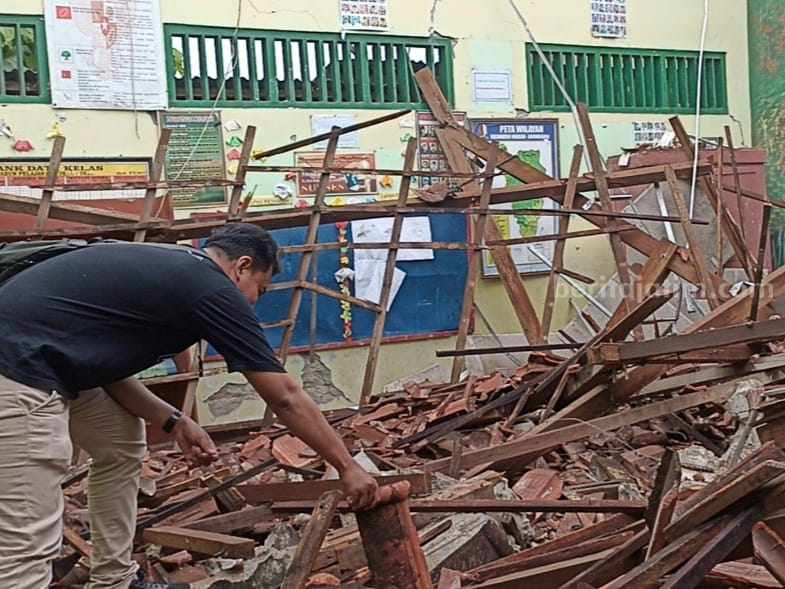 Seorang sedang mengecek kondisi kayu atap ruang kelas 6 SDN Ngadiluwih Kecamatan Ngasem Kabupaten Bojonegoro yang kondisinya ambrol.