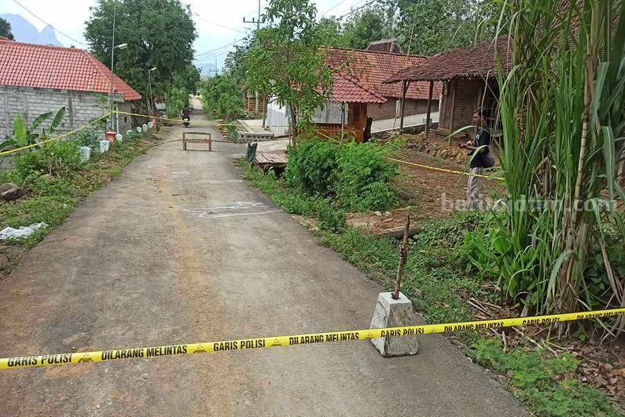 Polisi memasang garis polisi di jalan desa yang menjadi lokasi kejadian pembunuhan sesaat perayaan malah tahun baru, kemarin (01/01) (Foto/Endra Dwiono/Beritajatim.com)