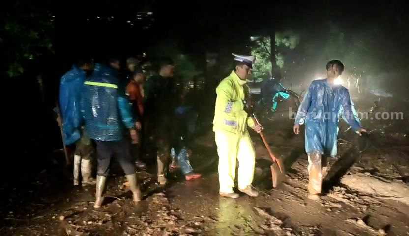 Petugas gabungan saat melakukan pembersihan material tanah longsor di jalan masuk Sarangan, Plaosan, Magetan, Jawa Timur, Jumat (5/1/2024)