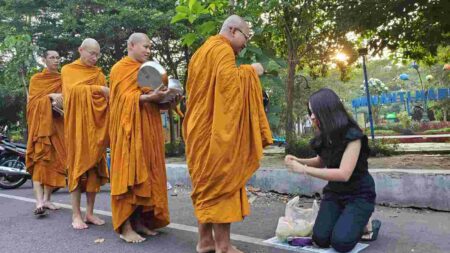 Salah satu warga membagikan dermanya ke para biksu dan biksuni di depan Taman Lalu Lintas, Perumahan Magersari Indah, Kecamatan Magersari, Kota Mojokerto. [Foto : ist]
