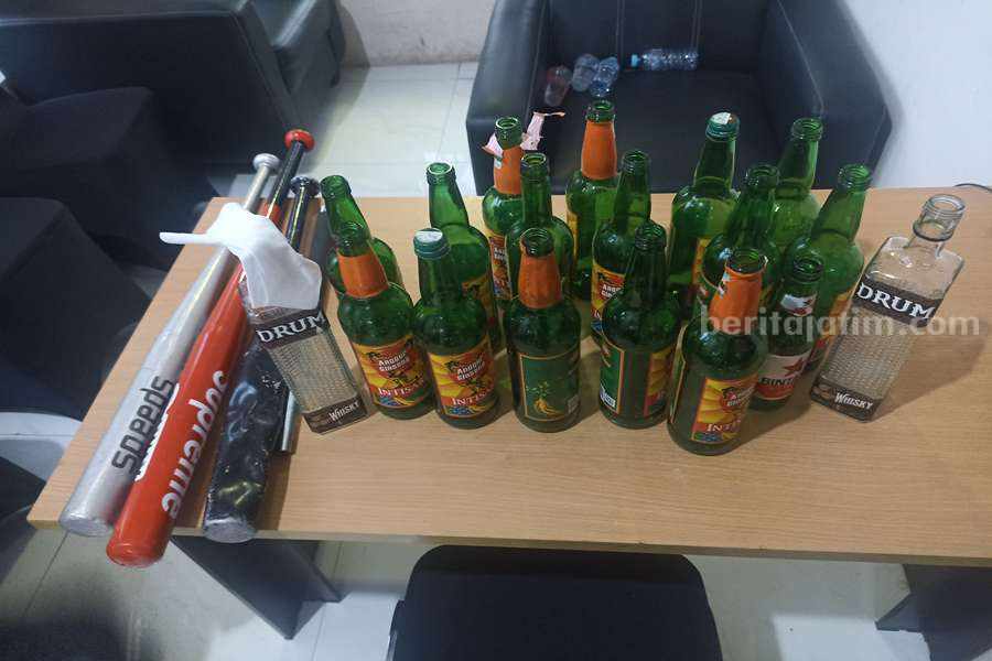 Botol minuman beralkohol dan tongkat baseball yang diamankan oleh petugas kepolisian.
