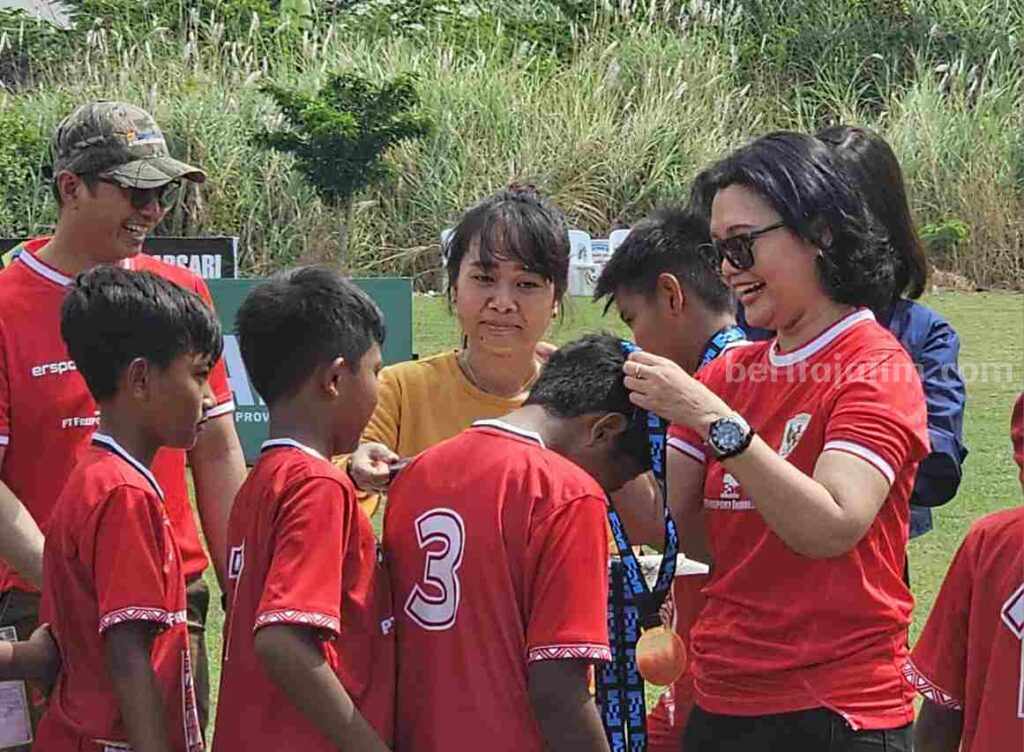 Foto Vice President Corporate Communications PTFI Katri Krisnati mengalungkan medali kepada pemain usia dini.