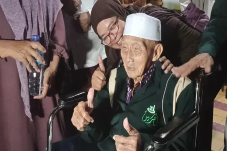 Pulang Selamat, Ini Cerita Perjalanan Spiritual Haji Tertua Indonesia asal Ponorogo Mbah Harjo Mislan mengacungkan 2 jempol tangannya, yang mengisyaratkan dirinya baik-baik saja. (Foto/Endra Dwiono/Beritajatim.com)