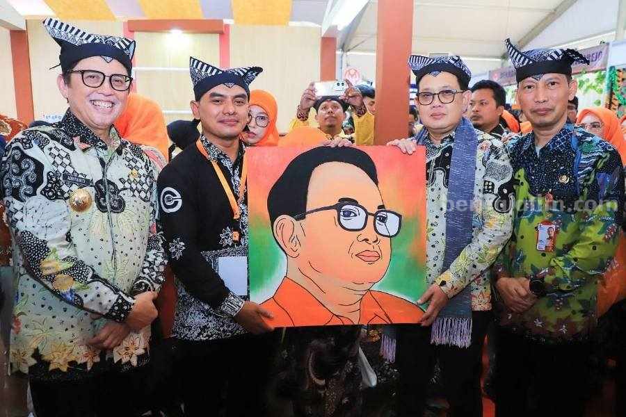 Adib Nurdiyanto saat menyerahkan lukisan hasil daur ulang limbah pewarna batik menjadi cat serbaguna kepada PJ Gubernur Jawa Timur Adhy Karyono. [Foto: Istimewa]