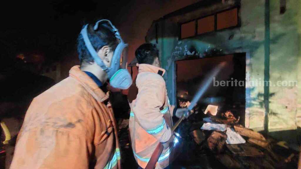 Petugas damkar memadamkan api yang membakar gudang furniture yang berada di kompleks Detasemen Zeni Bangunan I/V Sub Denzibeng 021/V di Jalan Raya Dusun Kenongo, Desa Mlirip, Kecamatan Jetis, Kabupaten Mojokerto. [Foto : ist]