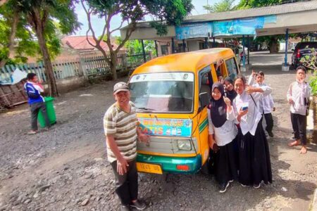 Asyik! Angkutan Pelajar Gratis Banyuwangi Hadir Lagi… Sejumlah siswa berpose bersama sopir di depan armada angkutan pelajar gratis di terminal Sasak Perot, Kelurahan Bakungan, Kecamatan Glagah, Banyuwangi.