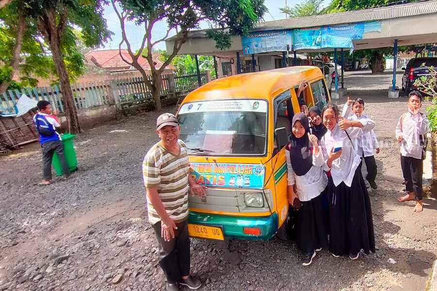 Sejumlah siswa berpose bersama sopir di depan armada angkutan pelajar gratis di terminal Sasak Perot, Kelurahan Bakungan, Kecamatan Glagah, Banyuwangi.