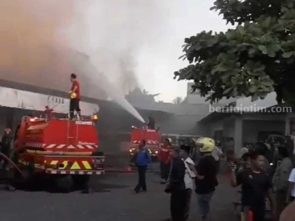 Petugas damkar berupaya memadamkan api yang membakar toko Puger.