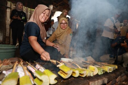Seorang warga melakukan proses pengasapan ikan pari bersama Bupati Banyuwangi Ipuk Fiestiandani di Dusun Sidomulyo, Desa Sumberberas, Kecamatan Muncar. (humaskab)