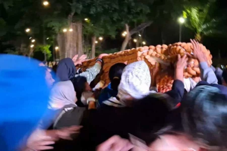 Sejumlah warga yang berebut Bolu Rahayu berbentuk lesung di Alun-Alun Magetan, Kamis (11/07/2024) malam.