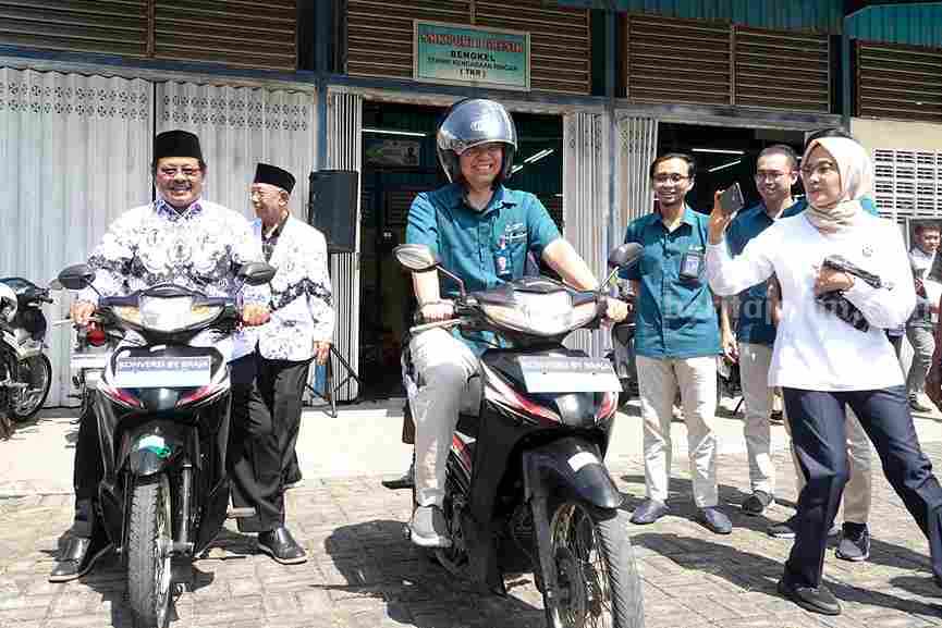 Direktur Keuangan dan Umum Petrokimia Gresik, Robby Setiabudi Madjid (tengah) saat mengendarai motor listrik hasil konversi siswa SMK.