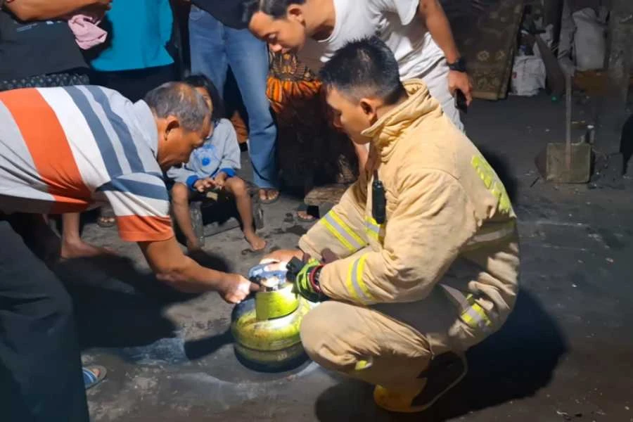 Petugas Damkar Magetan Dovi Saputra saat mengecek tabung gas milik Sutarmin yang terbakar dan menghebohkan warga pada Senin (01/07/2024) petang. (Foto: Fatihah Ibnu Fiqri/beritajatim.com)