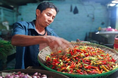 Harga Cabai Rawit di Surabaya Mulai Anjlok, Jadi Berkisar Rp45 Ribu hingga Rp80 Ribu Pedagang pasar di Surabaya menakar cabai rawit (dok. Rama Indra/beritajatim.com)