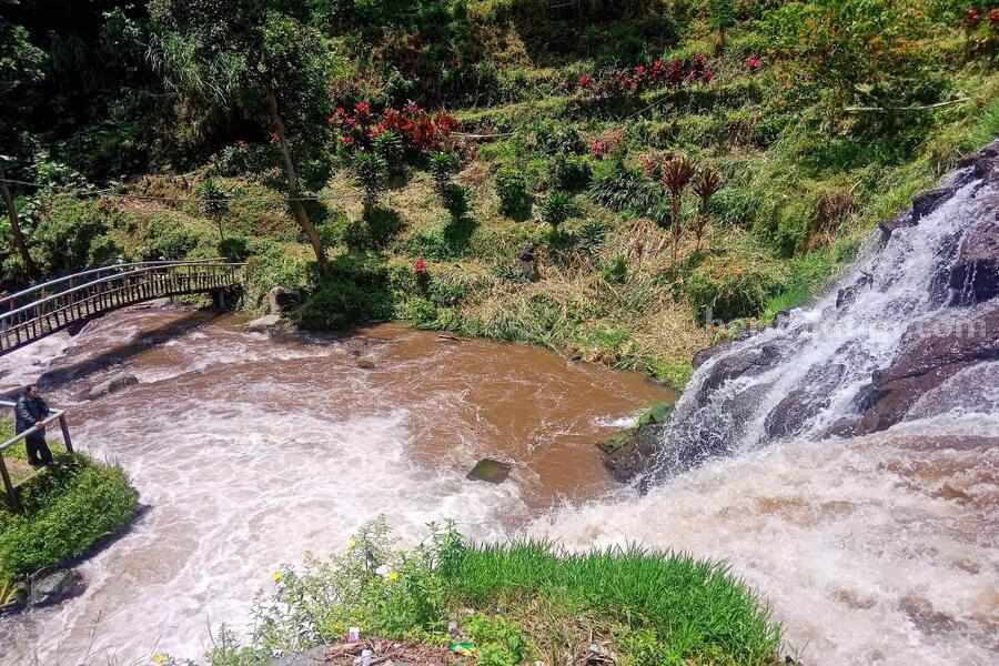 Seorang pengunjung berdiri memandangi Air Terjun Niagara Mini yang berada di Dusun Blawan, Desa Kalianyar, Kecamatan Ijen, Kabupaten Bondowoso. (Deni Ahmad Wijaya/BeritaJatim.com)