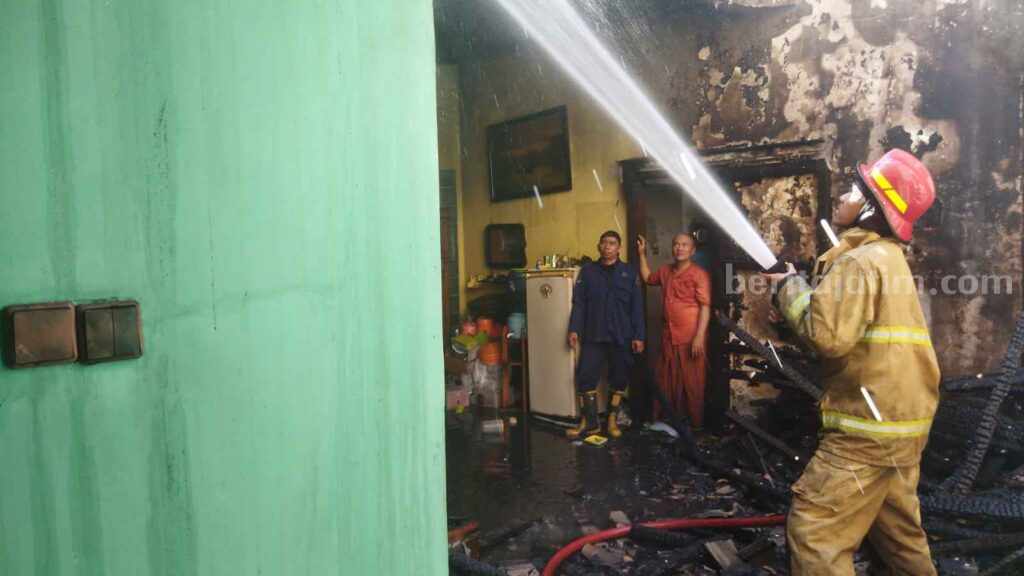 Petugas Damkarla Gresik dan petugas PMK Petrokimia Gresik saat melakukan pemadaman kebakaran rumah dua lantai di Perum Bakti Pertiwi (BP) Randuagung Kebomas, Gresik.