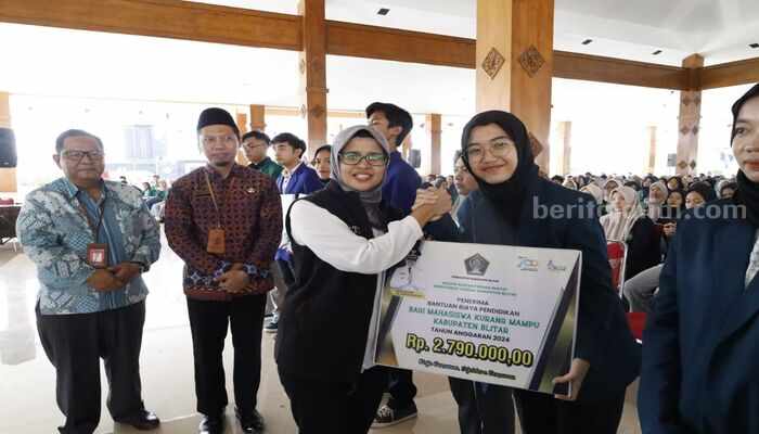 Bupati Blitar, Rini Syarifah memberikan beasiswa kepada mahasiswa secara simbolis, Senin (26/8/2024). (foto : Winanto/beritajatim.com)