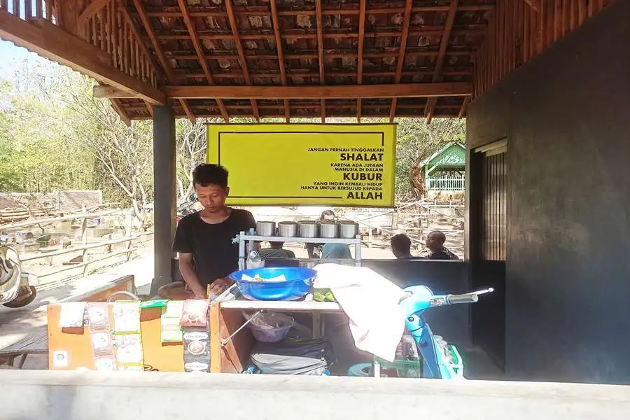 Rio Agung saat meracik kopi di warung kopi miliknya yang berada di area pemakaman. (Foto/Endra Dwiono/Beritajatim.com)
