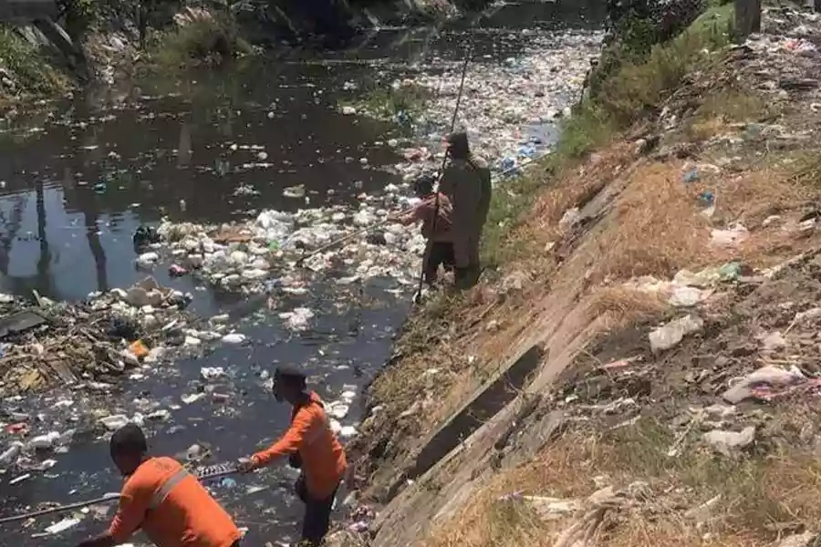 Petugas DLH membersihkan sampah di aliran sungai Jalan Wono Arum (Foto oleh DLH Kota Surabaya/Beritajatim.com) 
