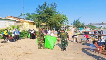 TNI bersama mahasiswa KKN dari Universitas Muhammadiyah Surabaya saat membersihkan pantai di Bulu Meduro. [foto: Diah Ayu/beritajatim.com]