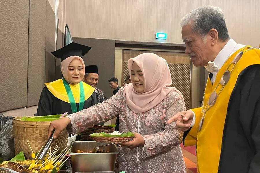 Lailatul Muharromah membagikan nasi boran kepada sivitas akademika Unusa saat momen wisuda di Dyandra Convention Hall Surabaya.