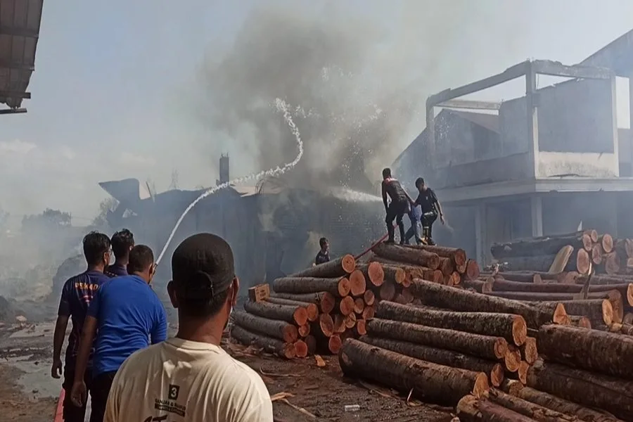 Petugas berusaha memadamkan api yang membakar gudang di pabrik triplek di Ponorogo. (Foto/Endra Dwiono/Beritajatim.com)