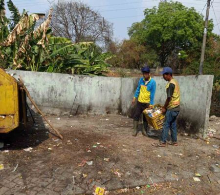 Dua petugas membersihkan sampah yang dibuang sembarangan oleh warga