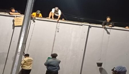 Potret warga lokal sekitar SBEC yang memanjat tembok untuk berjualan saat konser sedang berlangsung, Minggu (1/9/2024). (Fitri Yuliani/beritajatim.com)