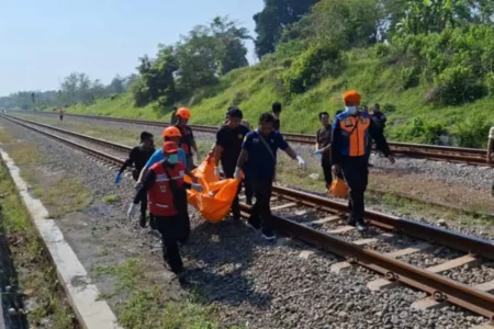 Petugas gabungan saat mengevakuasi jenazah pria tanpa identitas di pinggir rel masuk Desa Gendingan, Widodaren, Ngawi, Minggu (29/09/2024)