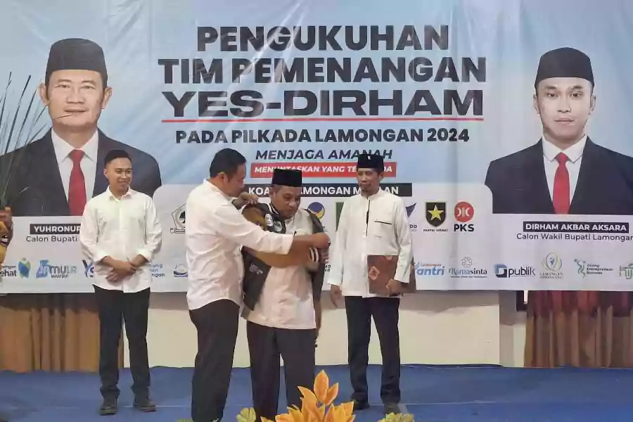Yuhronur Efendi secara simbolis memasangkan jaket kepada Ketua Tim Pemenangan, Imam Mukhlisin, saat pengukuhan di aula Hotel Mahkota Lamongan, Sabtu (7/9/2024).