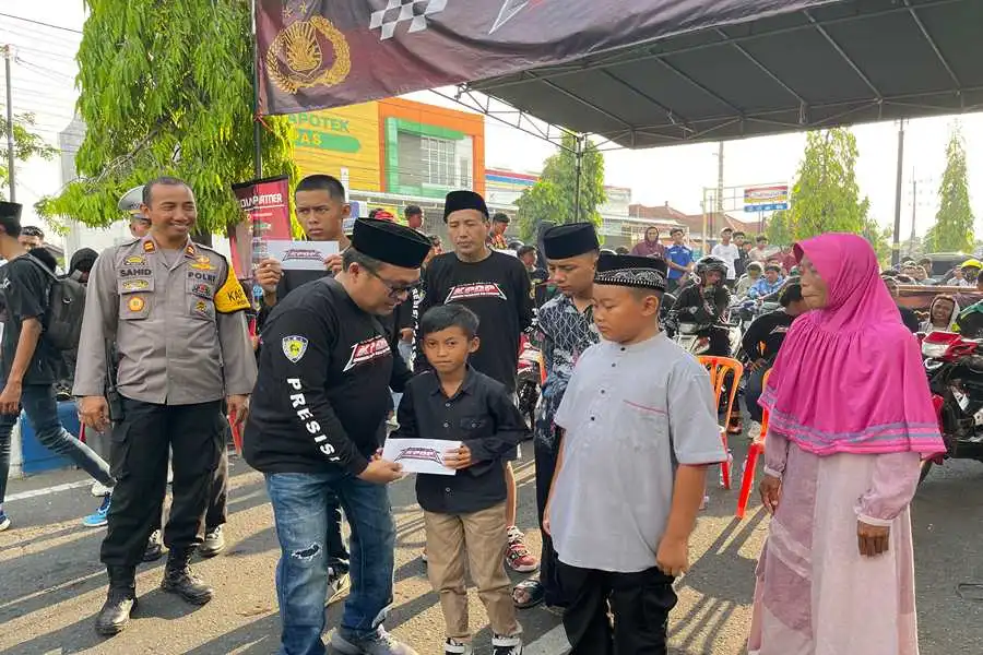 Anggota KPDP secara simbolis memberikan santunan terhadap janda, anak yatim dan dhuafa saat acara Latber Drag Bike di Jalan Juanda Ponorogo. (Foto/Istimewa)