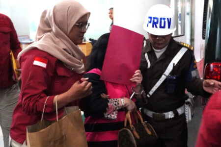 Tersangka Lisa Rahman (LR) menutupi wajah saat akan ditahan di Rumah Tahanan Negara Salemba Cabang Kejaksaan Agung. (Dok Kejaksaan Agung)
