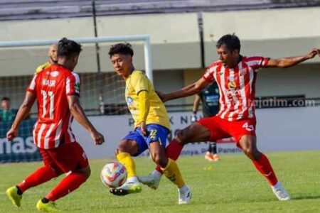 Gelandang Gresik United Ibnu Hajar (kuning) diapit dua pemain Deltras FC. (Foto: Gresik United)