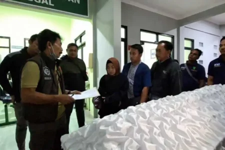 Petugas Satreskrim Polres Ngawi saat menyerahkan jenazah Darwati, ibu kos waega Beran Ngawi, usai proses autopsi, pada pihak keluarga, Selasa (15/10/2024).