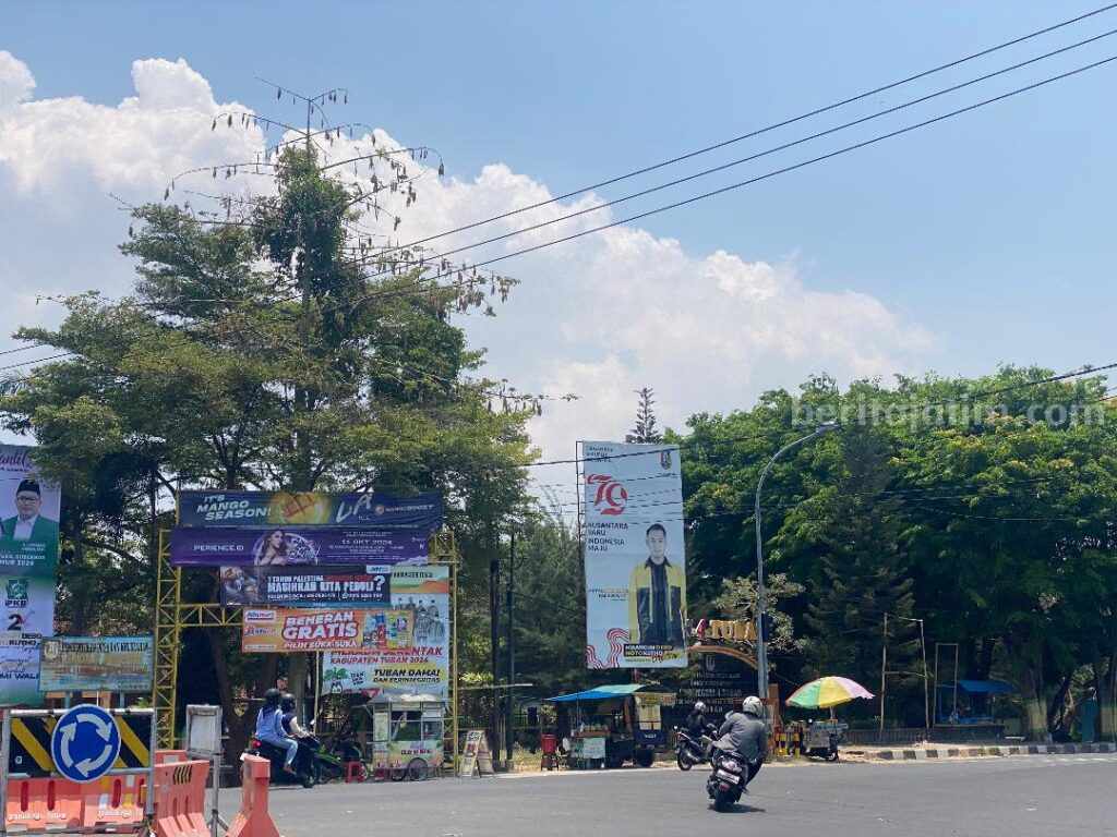 Baliho salah satu paslon atau petahana dengan logo Pemerintah Kabupaten Tuban yang masih terpasang di depan SMP Negeri 4 Tuban. [foto: Diah Ayu/beritajatim.com]