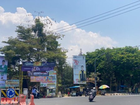Baliho salah satu paslon atau petahana dengan logo Pemerintah Kabupaten Tuban yang masih terpasang di depan SMP Negeri 4 Tuban. [foto: Diah Ayu/beritajatim.com]