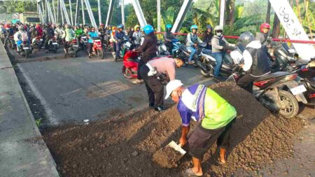Cegah Kecelakaan, Polisi dan Warga Tambal Jalan Berlubang di Jalur Penghubung Gresik–Sidoarjo Foto BeritaJatim.com